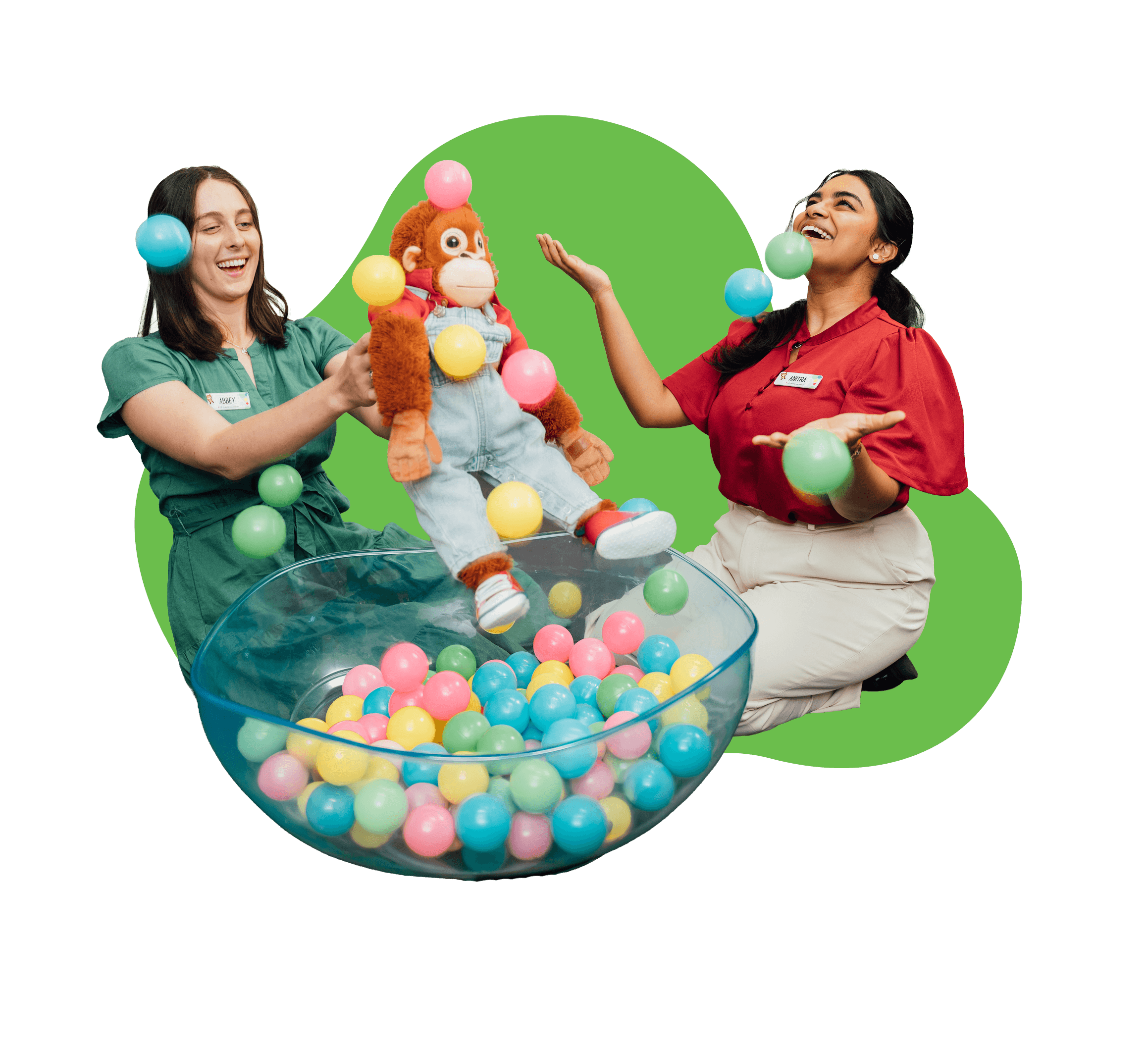 Two employees and George playing in the ball pit