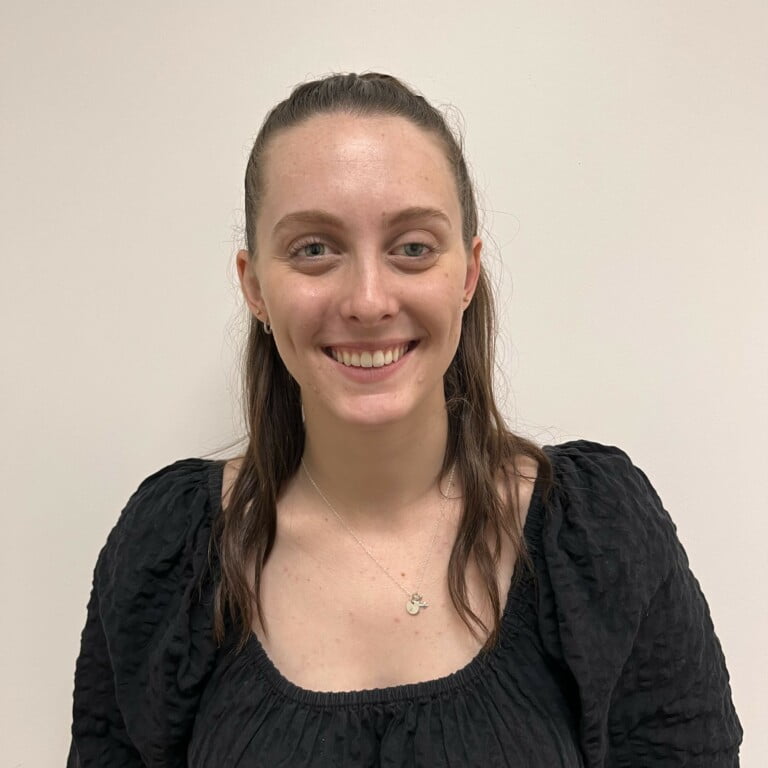 A woman in a black top smiling in front of a white wall at Crompton Abbey.